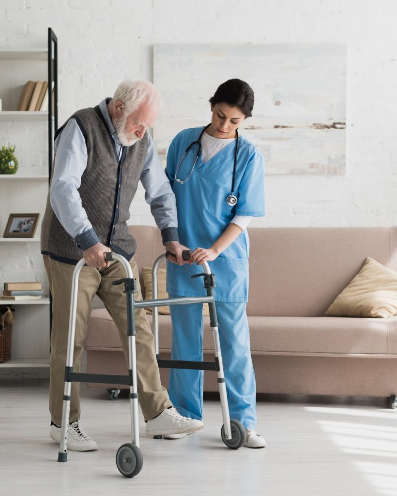 Nurse helping to senior man walking at home, recovering after injury